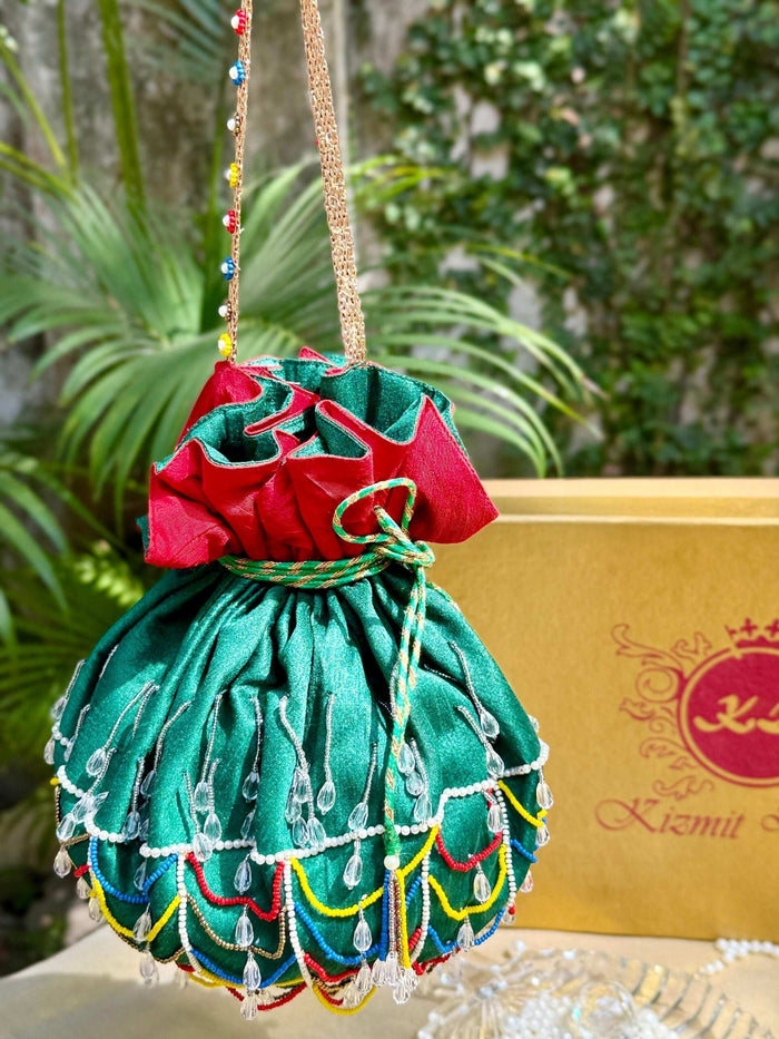 Beaded handle and drawstring of the green potli bag, gift box and greenery behind