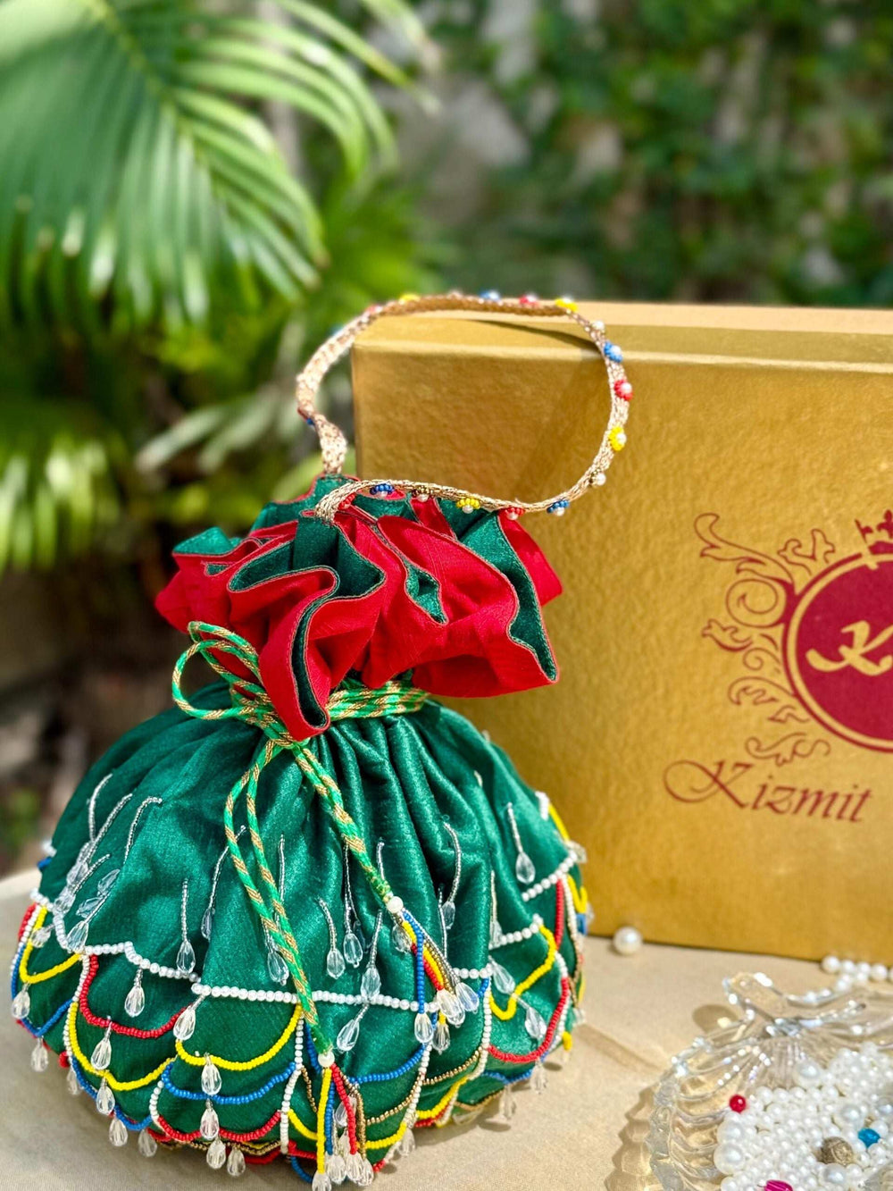 Front of the beaded potli bag with its red ruffled drawstring top and long beaded handle