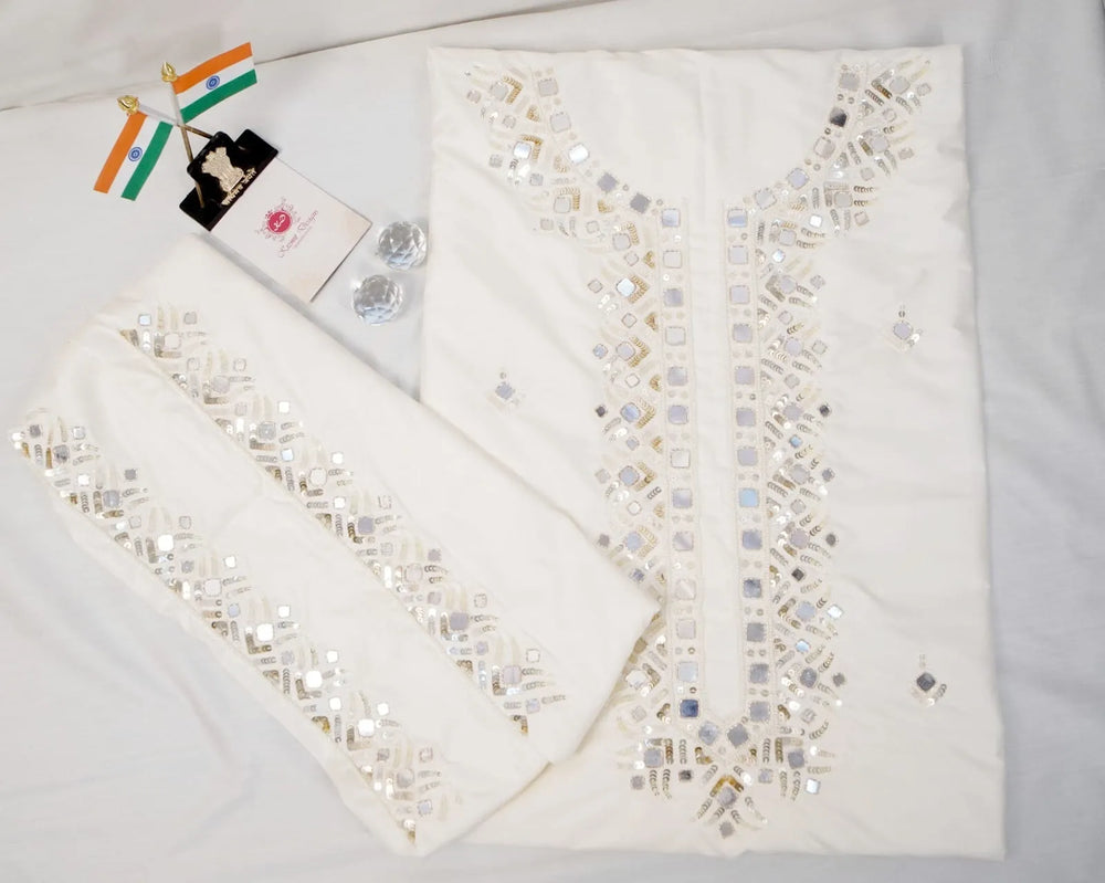 Unstitched white suit set laid flat, kurta piece and mirror-worked sleeve panels