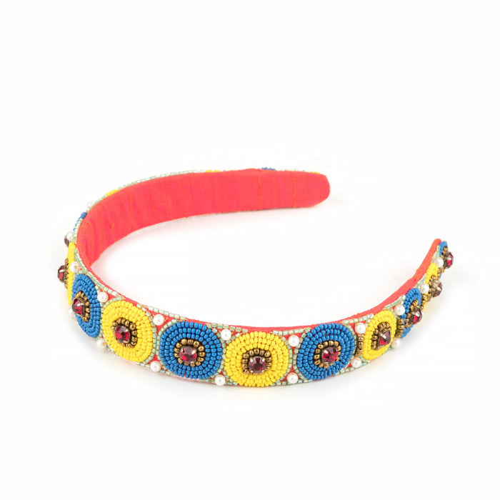 Coral headband with blue and yellow beadwork discs, angled view on white
