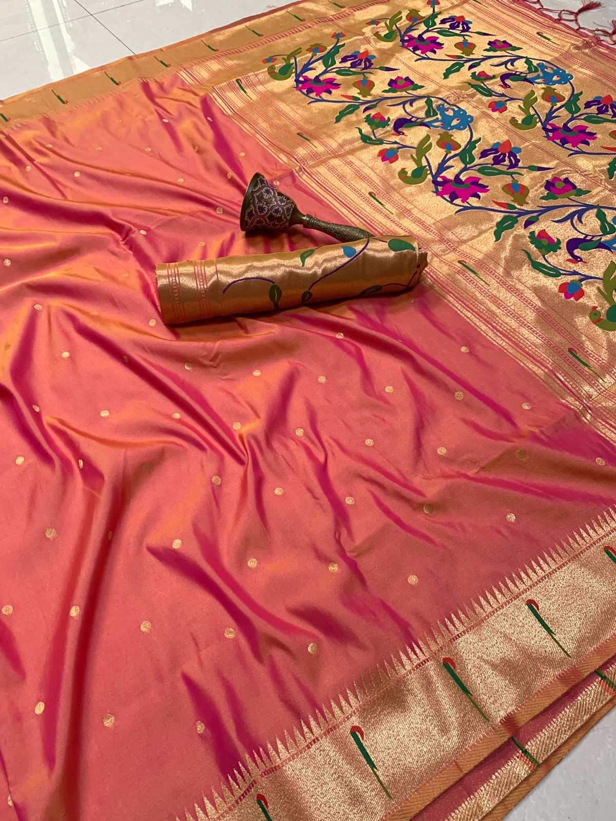 Peach Paithani saree with zari bootis and peacock motif pallu folded behind the blouse piece