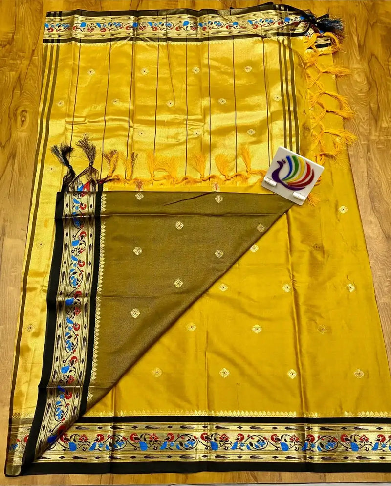 Yellow Paithani saree laid flat, gold zari pallu with tassels and black peacock border