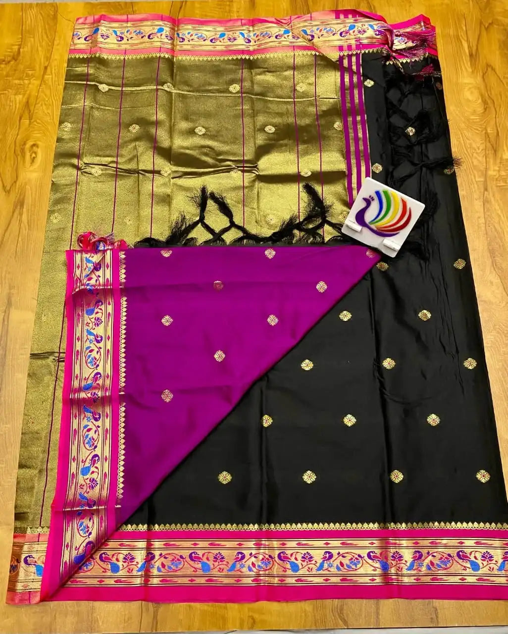 Black Paithani saree spread flat, gold zari pallu with tassels and rani pink peacock border