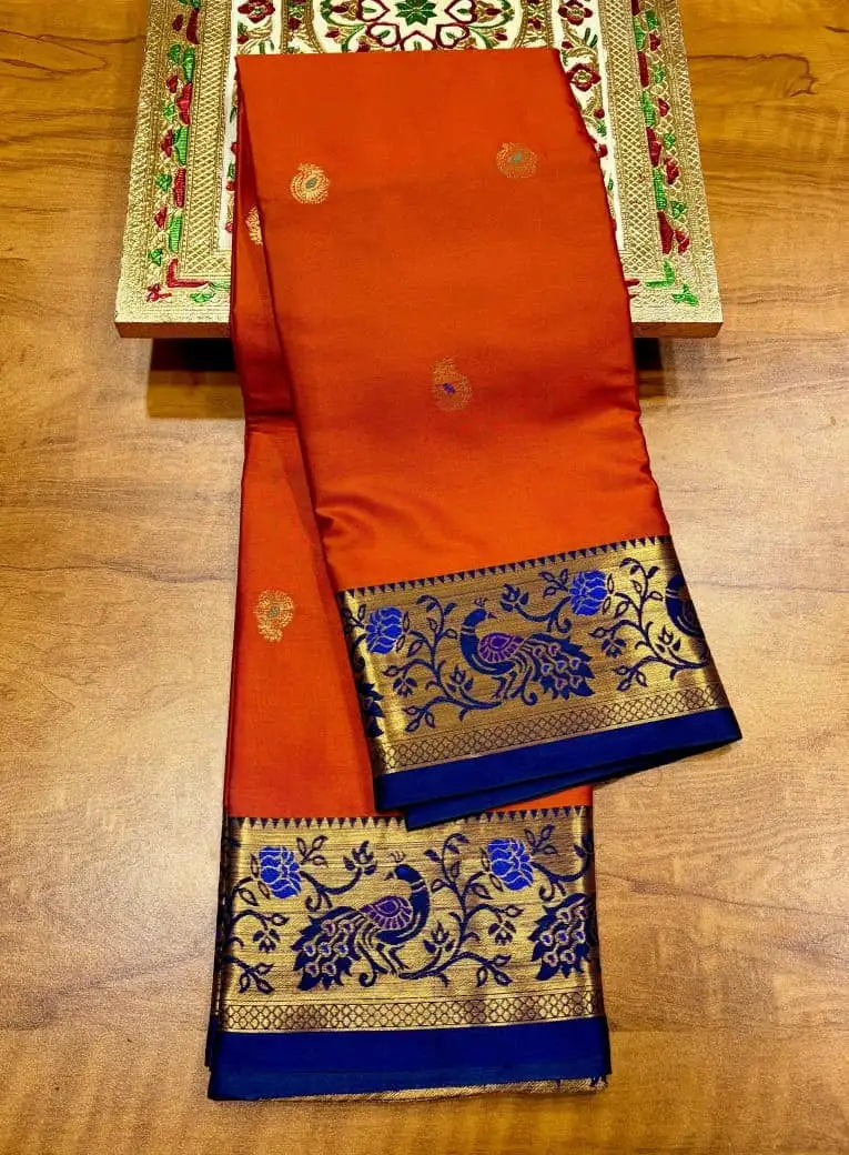 Orange soft silk saree in folds, blue border and pallu woven with gold peacock motifs