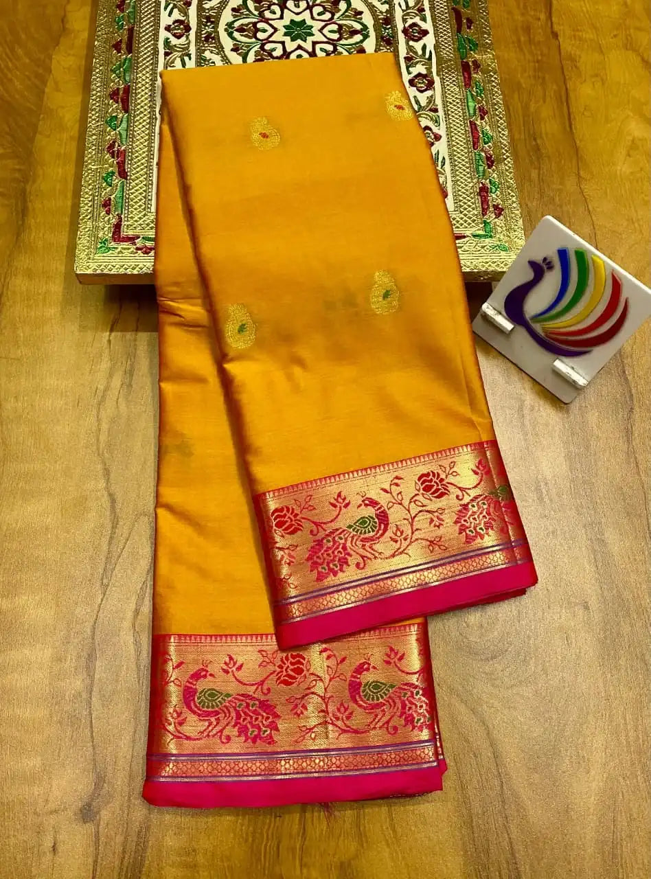 Yellow soft silk Paithani saree folded, pink border with gold peacock weave