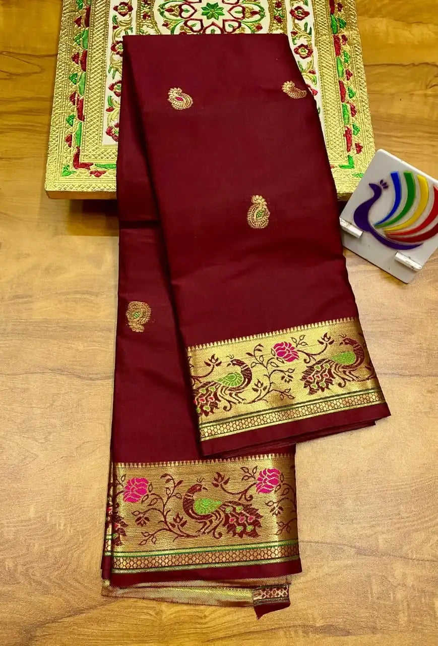 Maroon brocade Paithani saree folded, gold zari border woven with peacocks and flowers