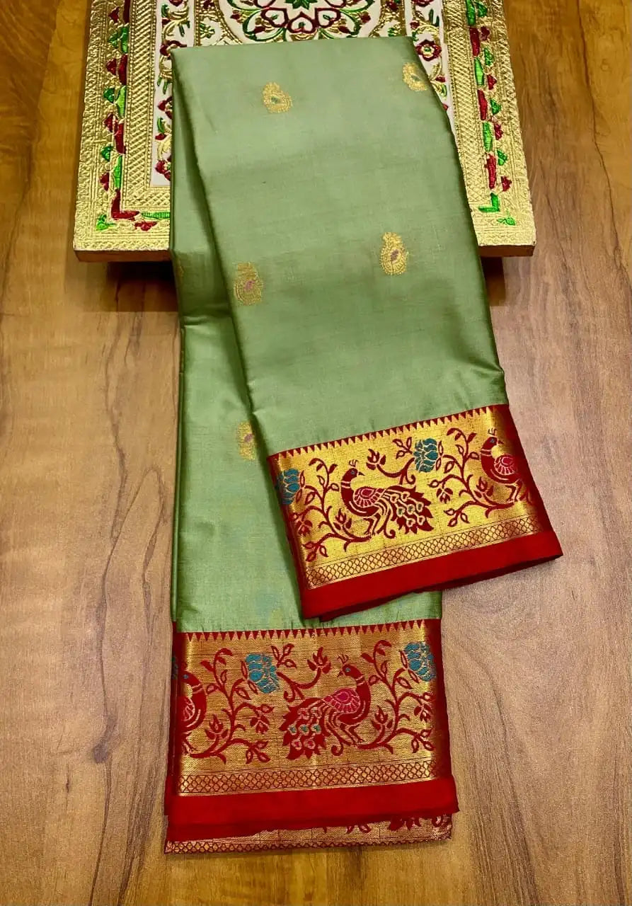Sage green soft silk Paithani saree folded beside its red peacock brocade border