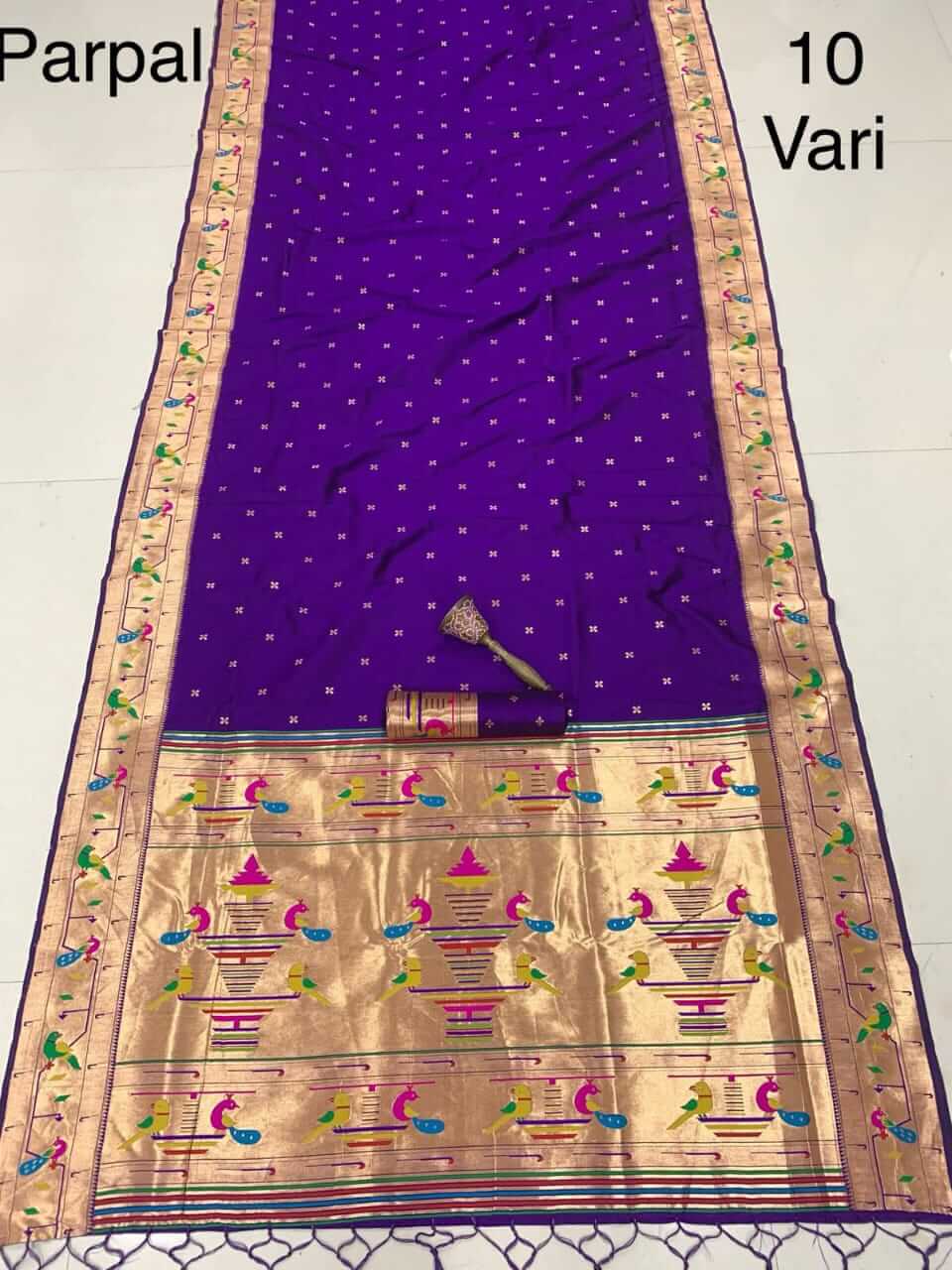 Purple saree laid flat with a rolled blouse piece, gold pallu of peacocks and flowerpots