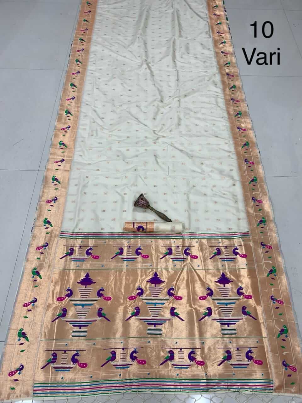 Off-white saree spread full length, copper zari border and peacock-filled tissue pallu