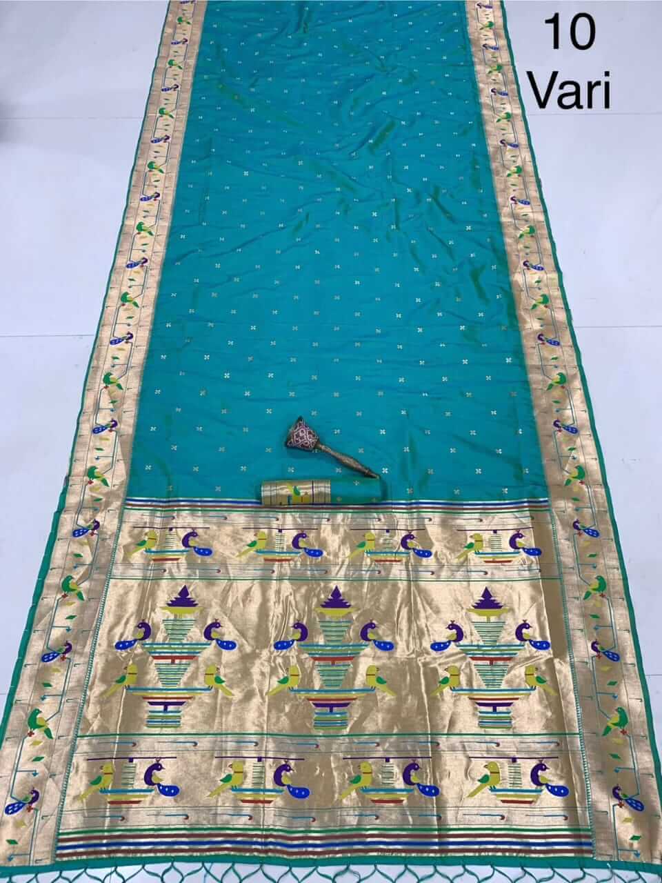 Teal blue saree laid out with fine zari bootis and a gold pallu of peacocks and vases