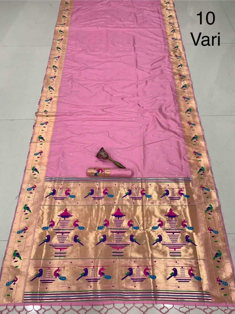 Light pink saree laid out full length, copper zari border and peacock-patterned tissue pallu