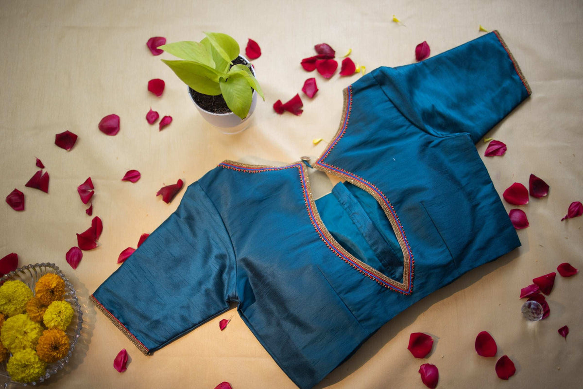 Teal blouse laid flat back up, short sleeves and button loop closure