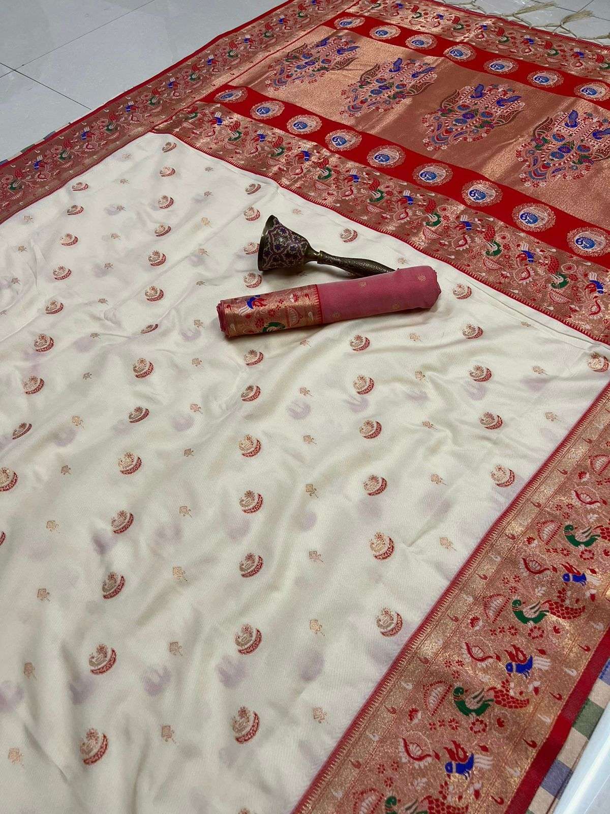 Off-white Paithani saree with red peacock border, flat-laid with blouse piece