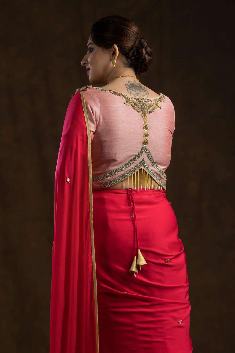 Back of the peach blouse showing gold and green embroidered yoke with hanging zari fringe
