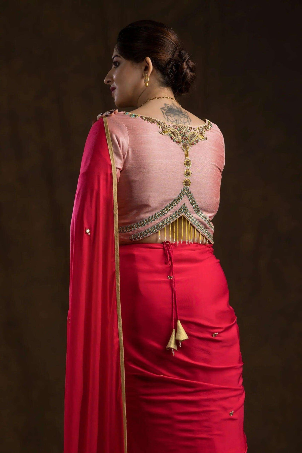 Back of the peach blouse showing gold and green embroidered yoke with hanging zari fringe
