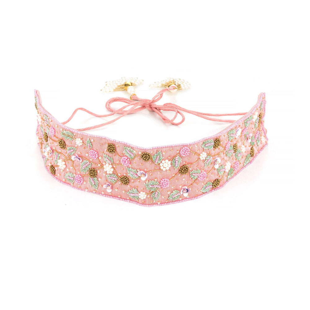 Pink beaded saree belt curved on white, tie cords with pearl cluster tassels laid above
