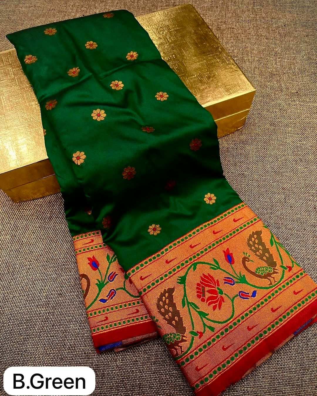 Bottle green saree folded over a gold box, lotus and peacock border in red and gold