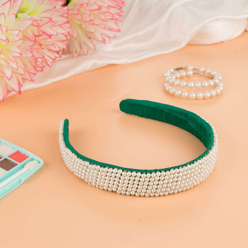 Pearl headband on a peach surface with a pink dahlia, pearl bracelet and eyeshadow palette