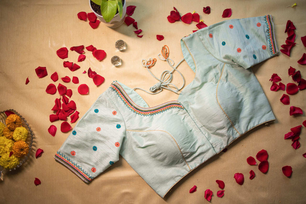 Padded front of the pistachio blouse laid among red rose petals