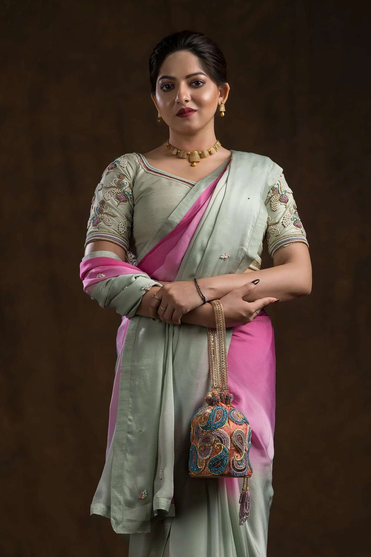 Model in the pistachio blouse and pink ombre saree, holding an embroidered potli