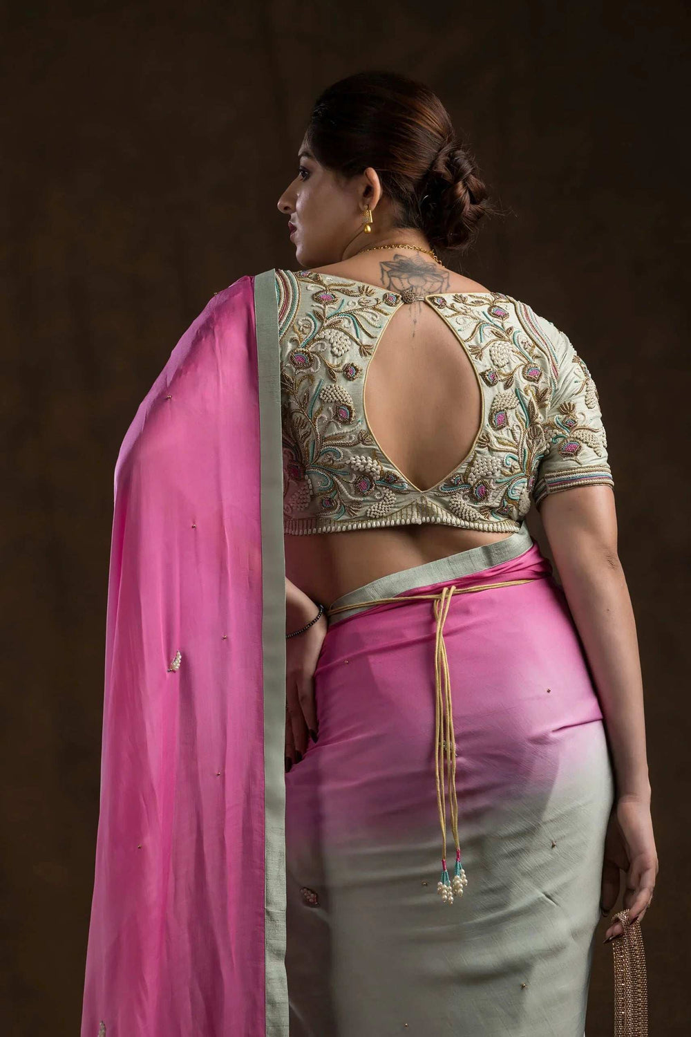 Pearl-edged hem and floral zardozi across the blouse back, model turned away