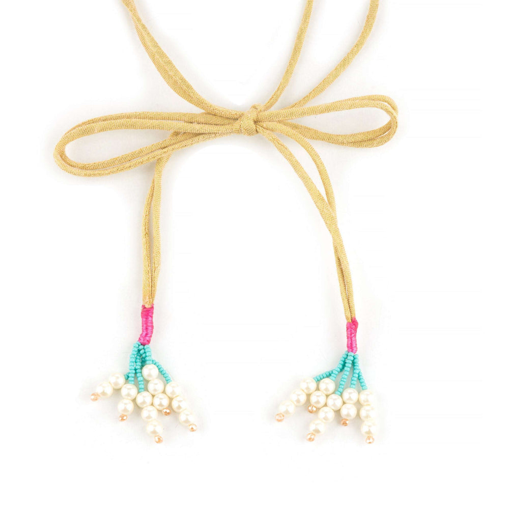 Suede tie cords knotted in a bow ending in pearl cluster tassels