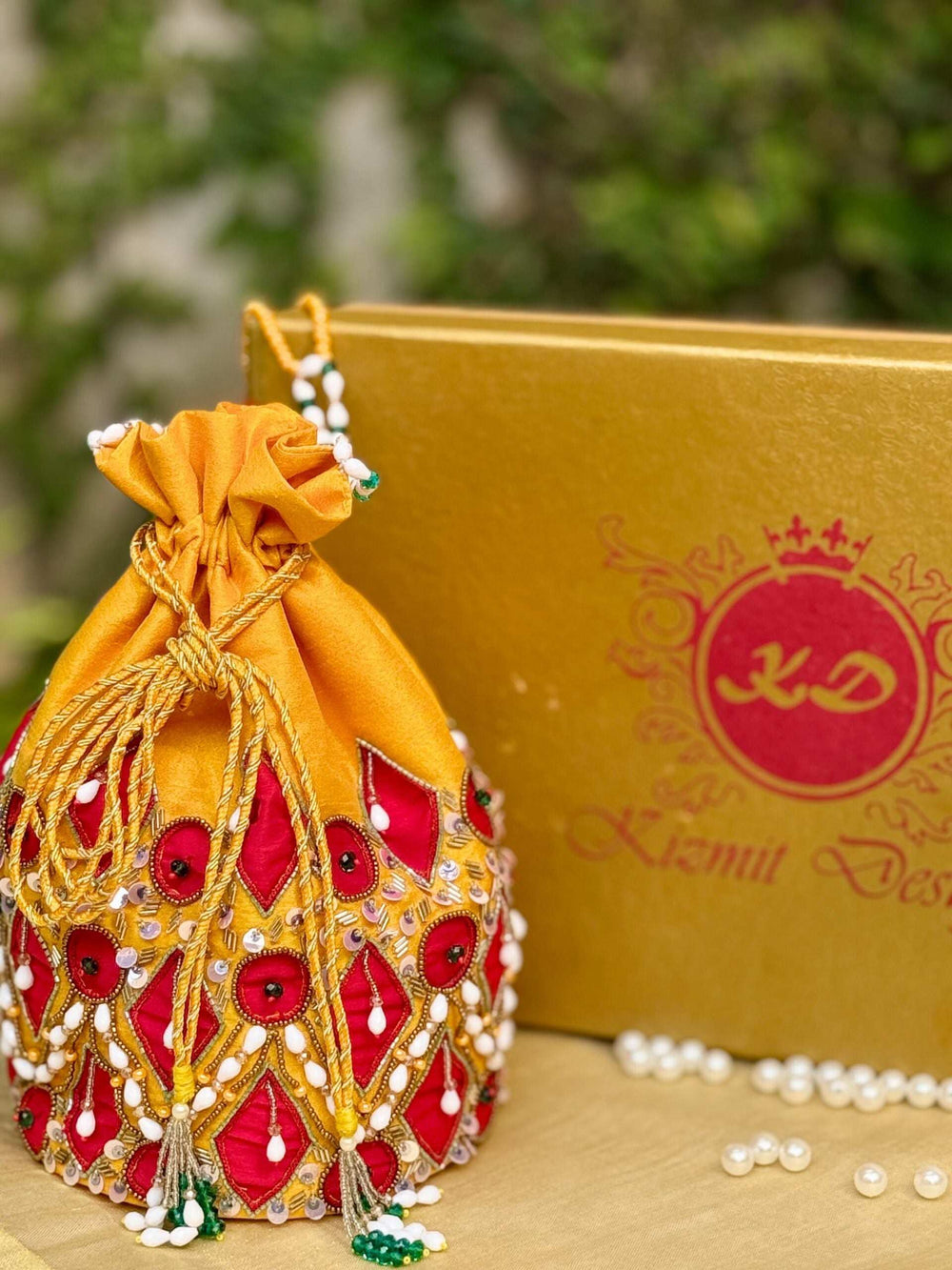Mustard potli drawn shut, standing beside a gold Kizmit Designs box