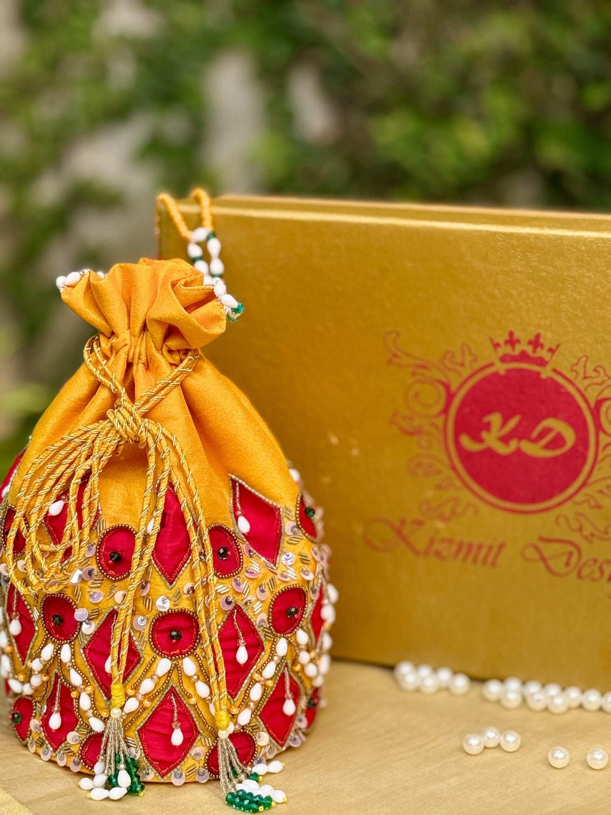 Mustard potli drawn shut, standing beside a gold Kizmit Designs box