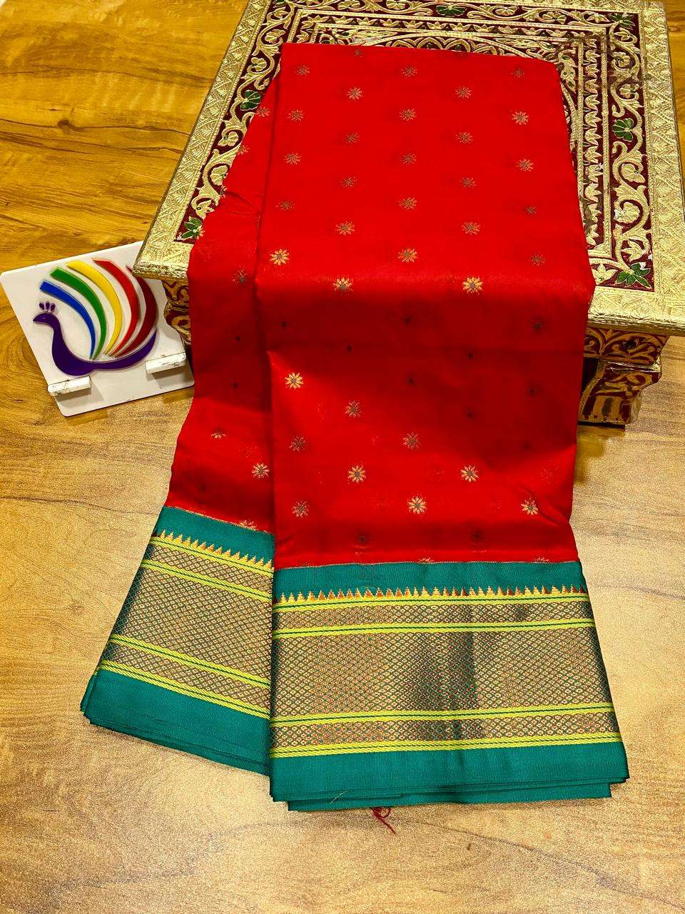 Red saree with gold bootis and a contrast green kadiyal border, folded on a table