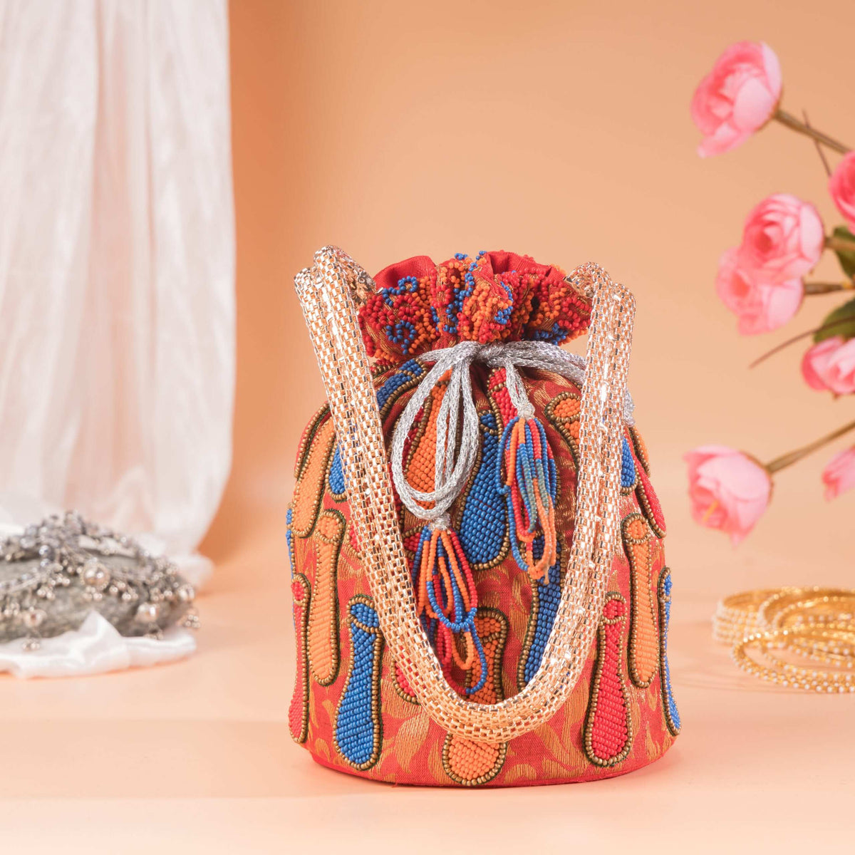 Potli bag with its drawstring gathered top and twin gold handles looped upright