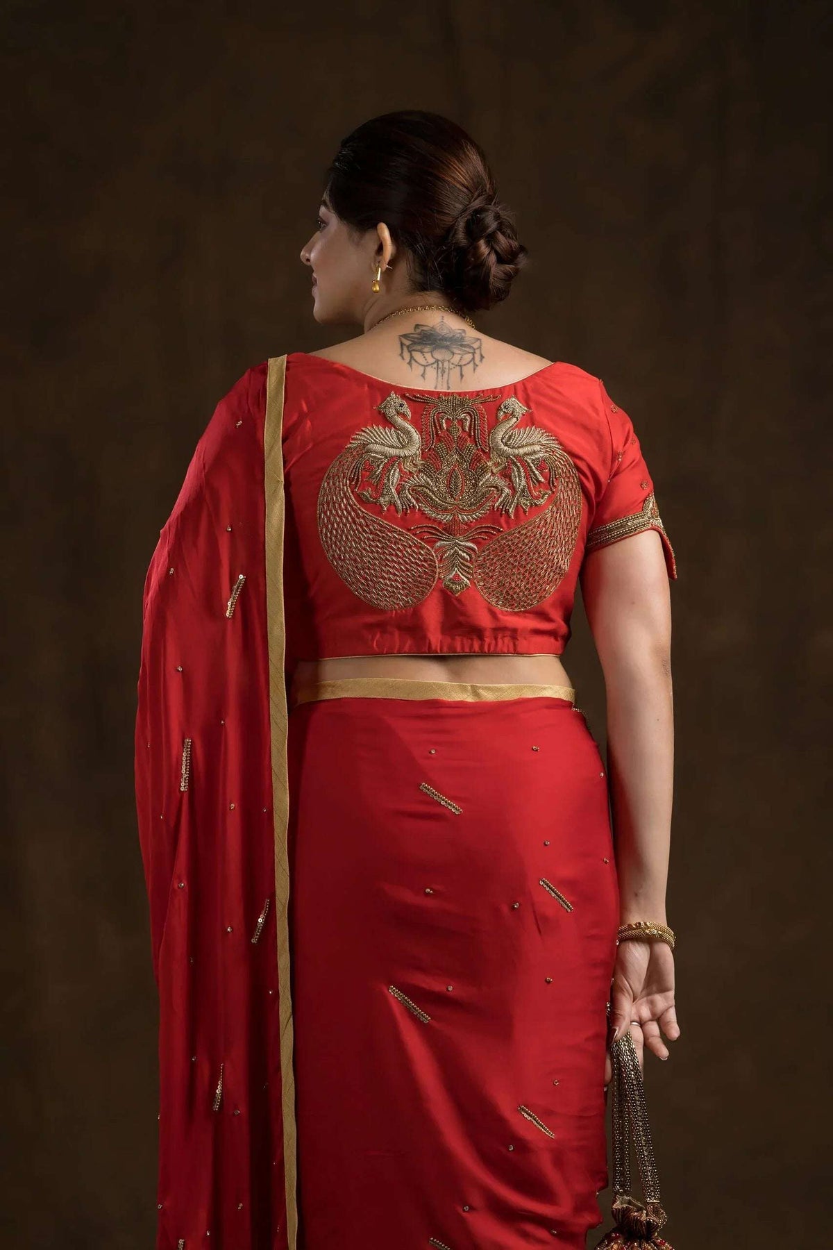 Back of the red blouse with gold peacock embroidery over a red saree drape