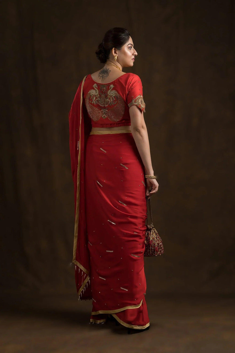 Full-length back view, red mayur blouse with red saree and red potli bag
