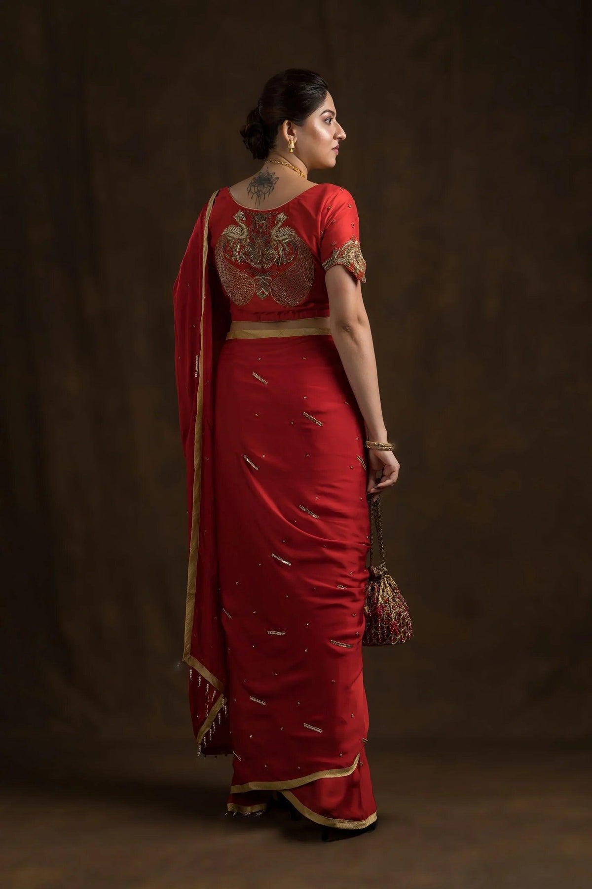 Full-length back view, red mayur blouse with red saree and red potli bag