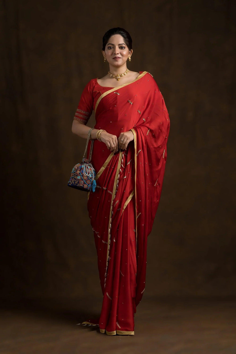 Full-length front view of the red blouse worn with a gold-bordered red saree