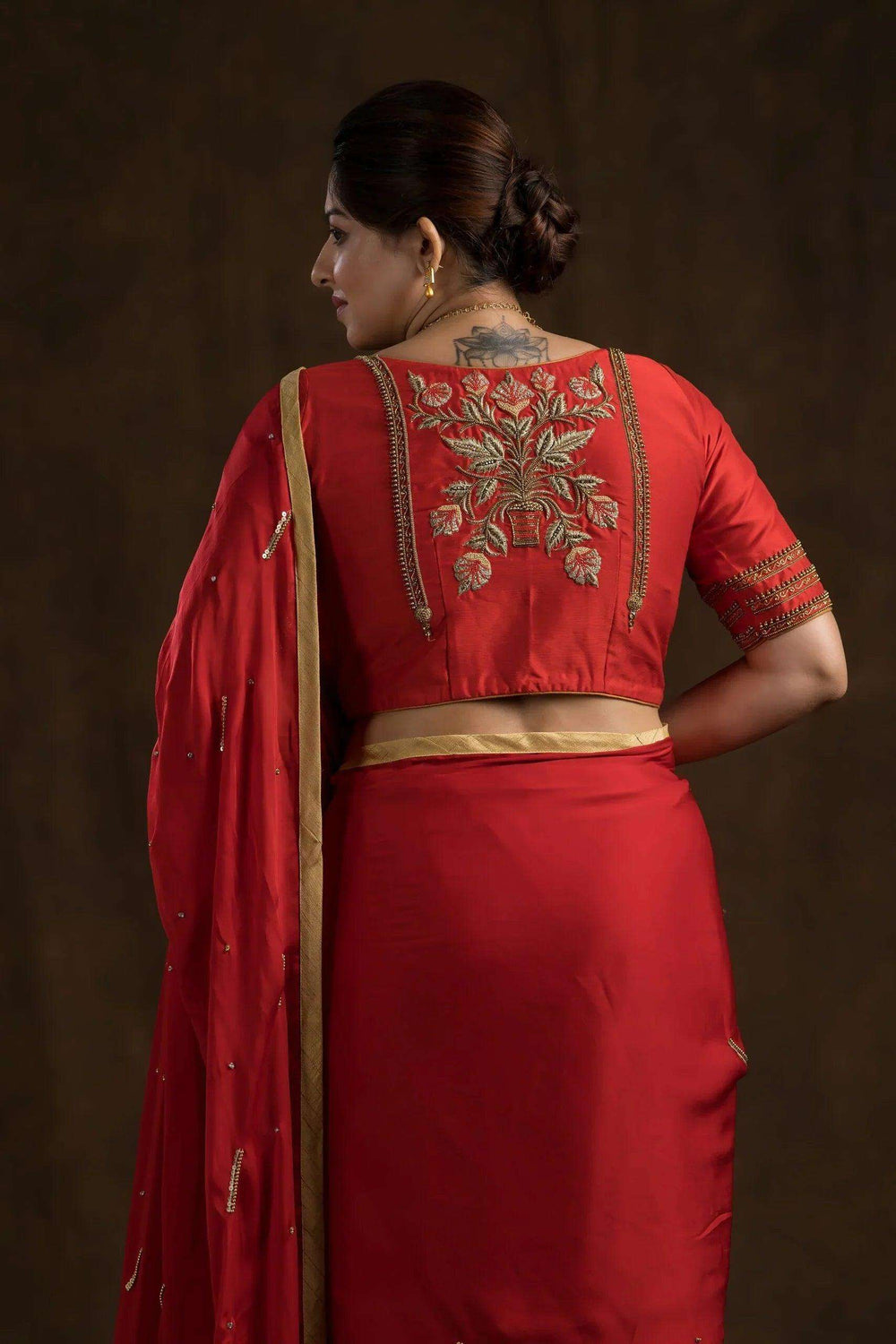 Back of the red blouse showing the floral embroidery panel and zari-worked sleeve edges