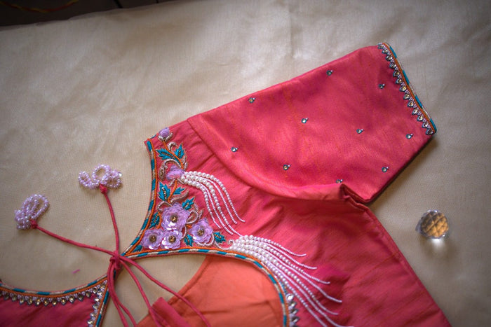 Rosette and pearl embroidery running along the shoulder and sleeve, angled close-up