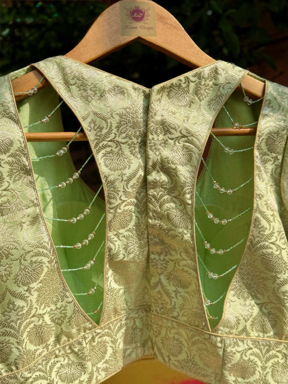 Deep V back cut-out strung with fine crystal bead chains over plain green lining