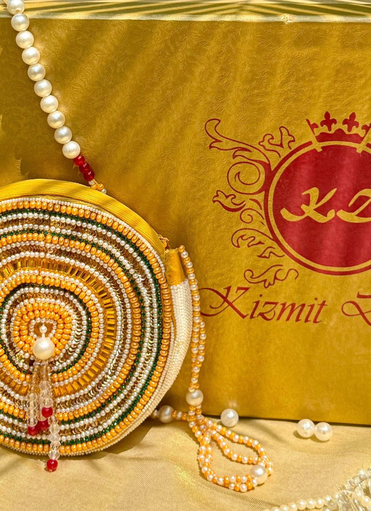 Concentric rings of yellow, green and red beadwork with a crystal drop tassel, close-up