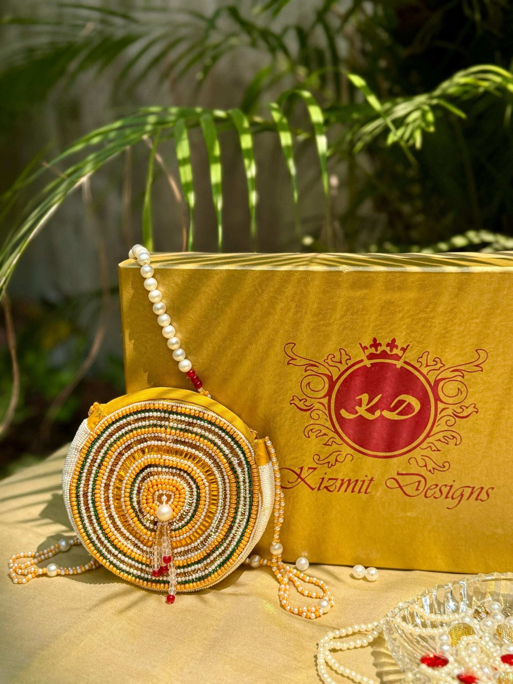 Circular beaded bag propped upright, pearl strands and tassel resting on the cloth