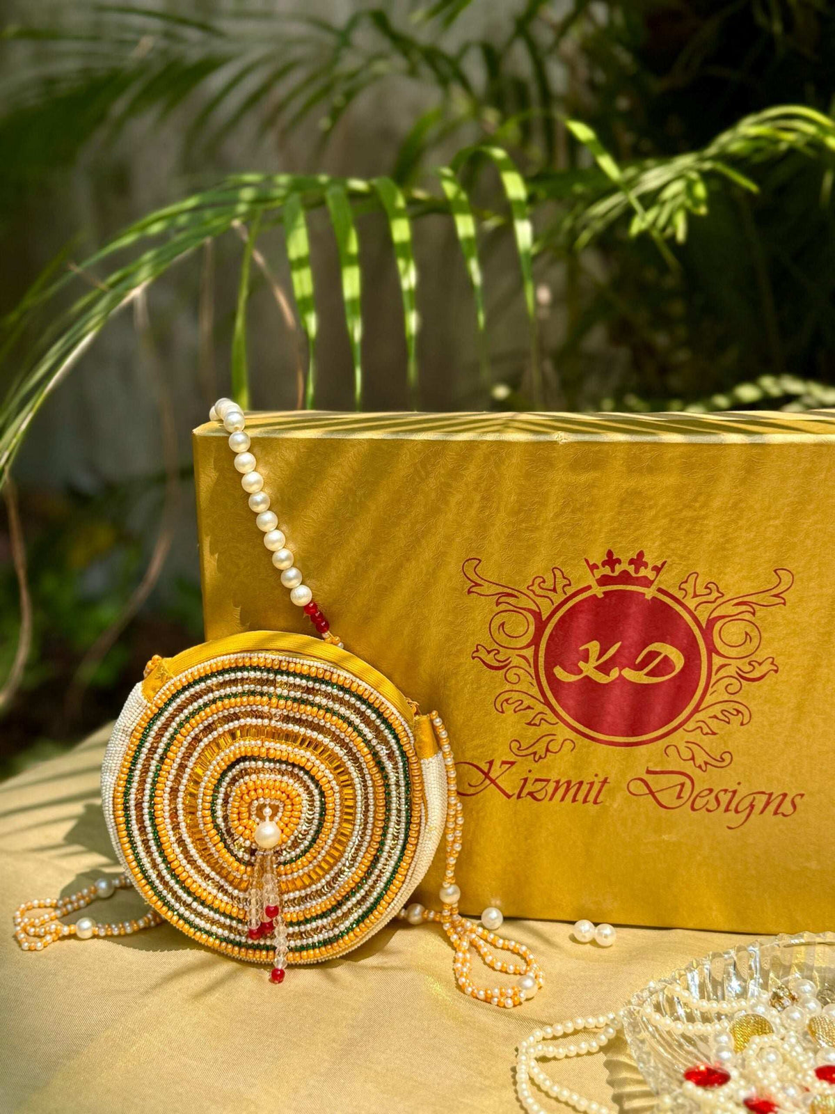 Circular beaded bag propped upright, pearl strands and tassel resting on the cloth