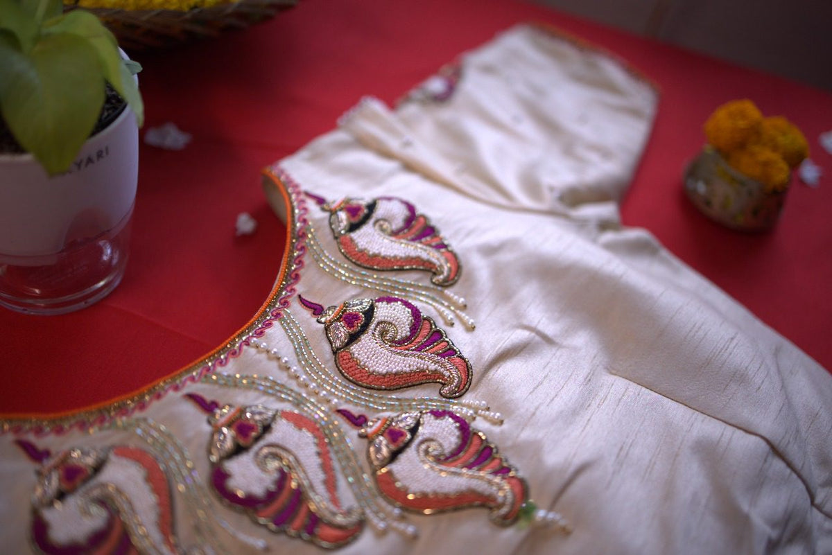 Neckline embroidery close-up, conch motifs worked in pink, orange and gold beads