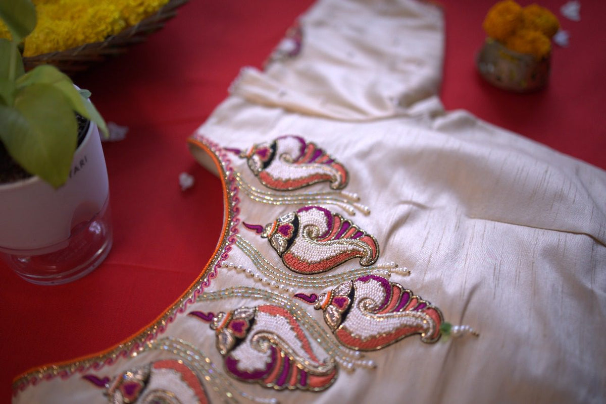 Row of beaded conch motifs following the curved neckline, photographed at an angle