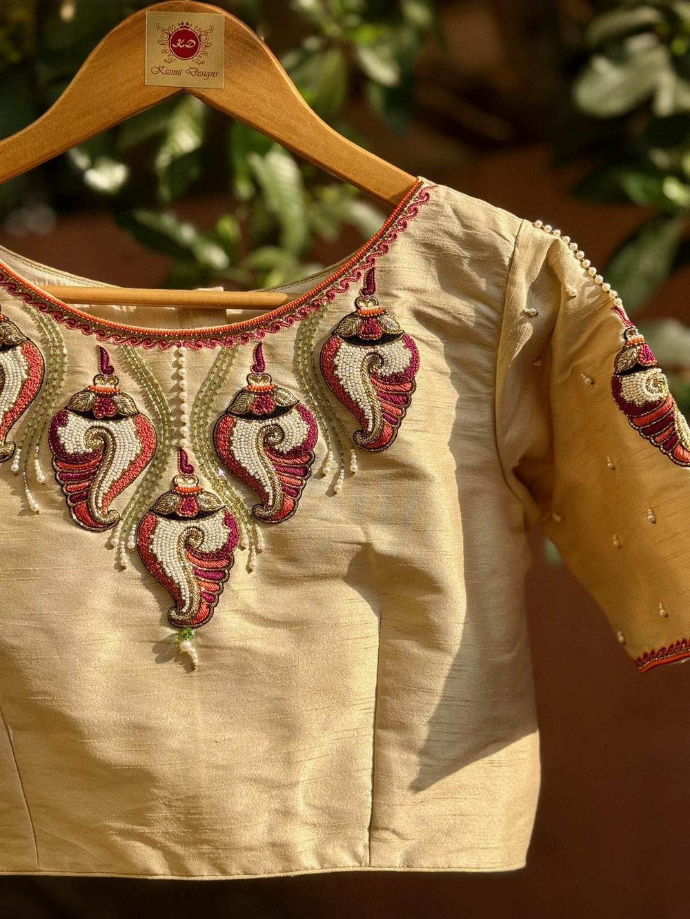 Front of the embroidered blouse on a wooden hanger, motifs ringing the round neck