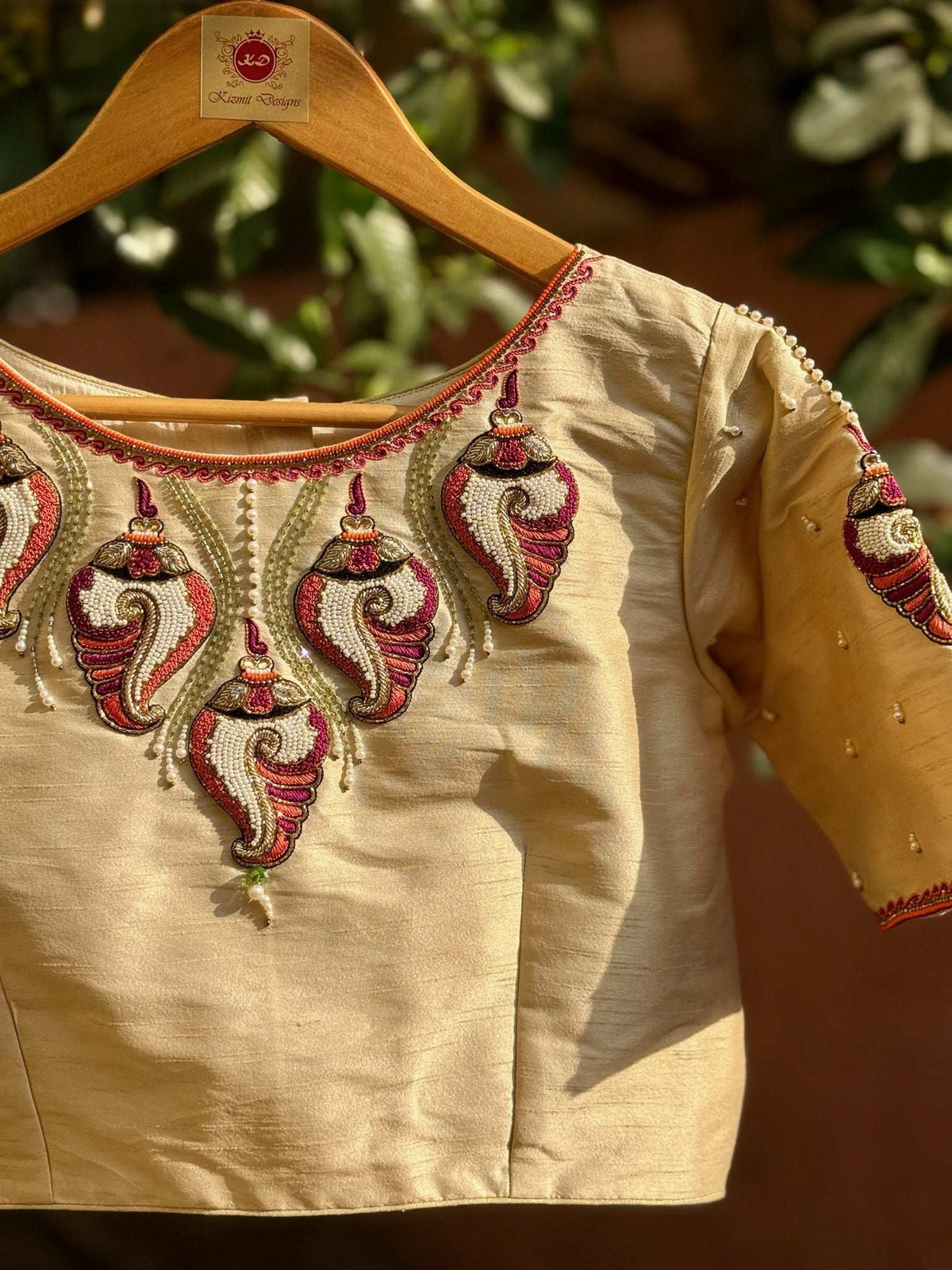 Front of the embroidered blouse on a wooden hanger, motifs ringing the round neck