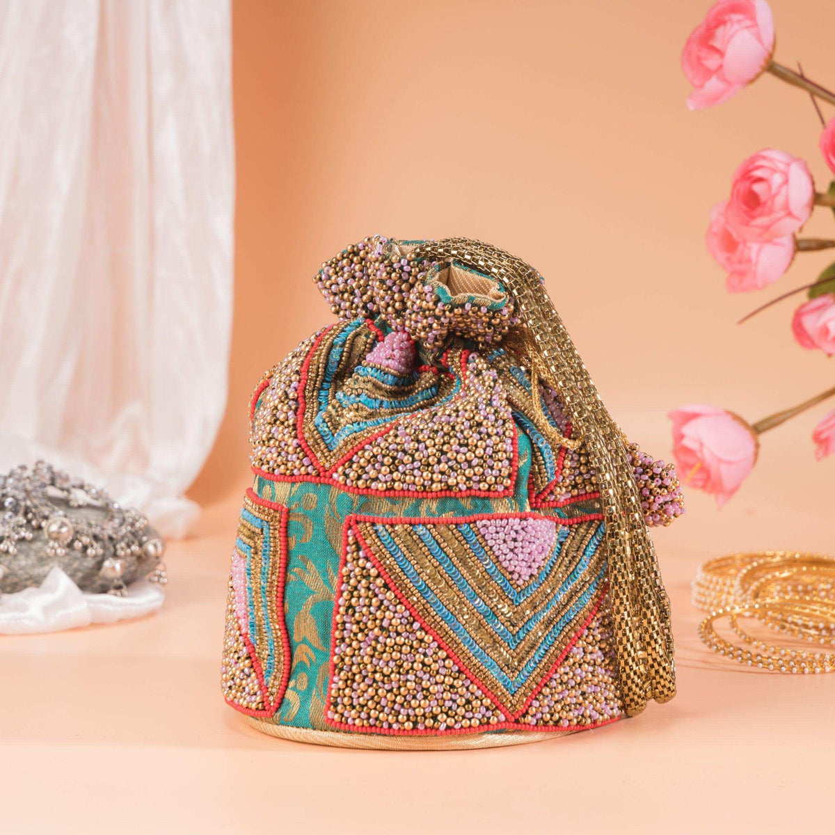 Side of the beaded potli showing turquoise and pink mosaic panels and a beaded tassel