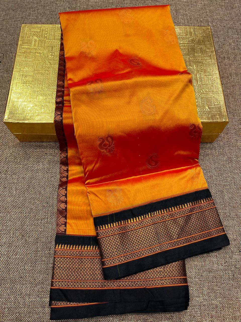 Marigold orange saree body with maroon bootis and a black border in gold brocade