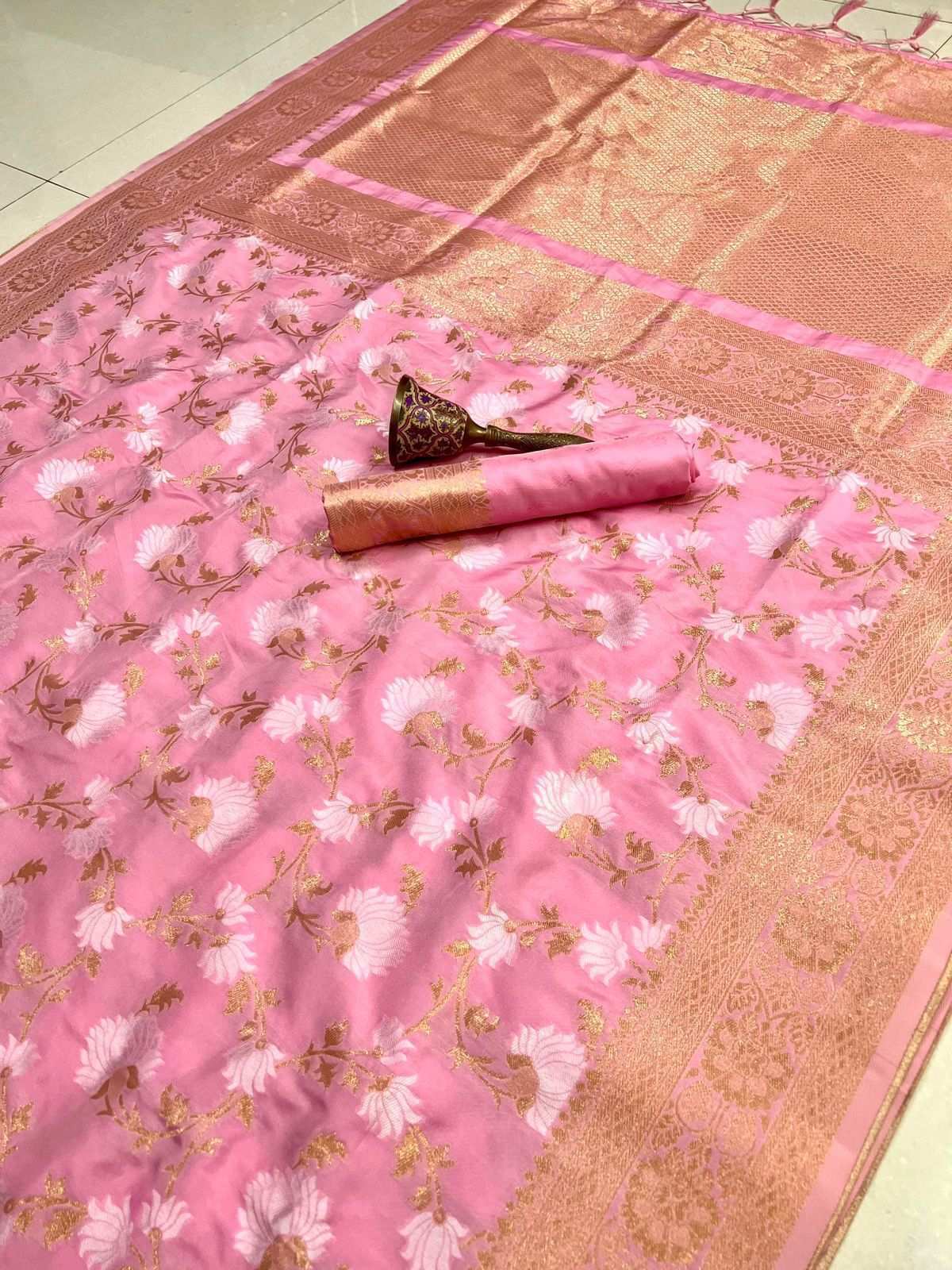 Pink semi silk saree laid flat, white floral jaal with gold zari pallu and blouse piece