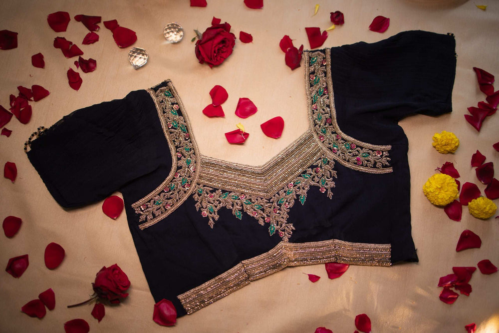 Sharvya hand embroidered blouse laid flat, navy with gold zari and green-pink stone work
