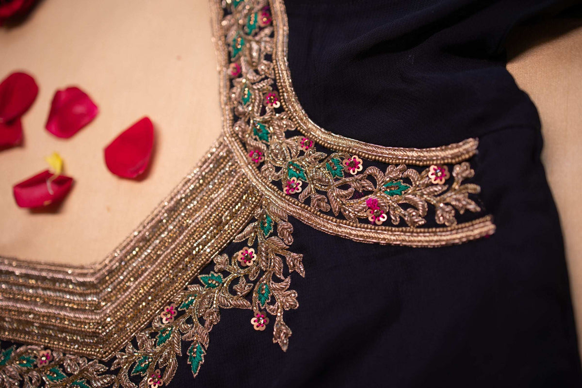 Angled macro of the shoulder and neckline embroidery, gold beads over navy fabric