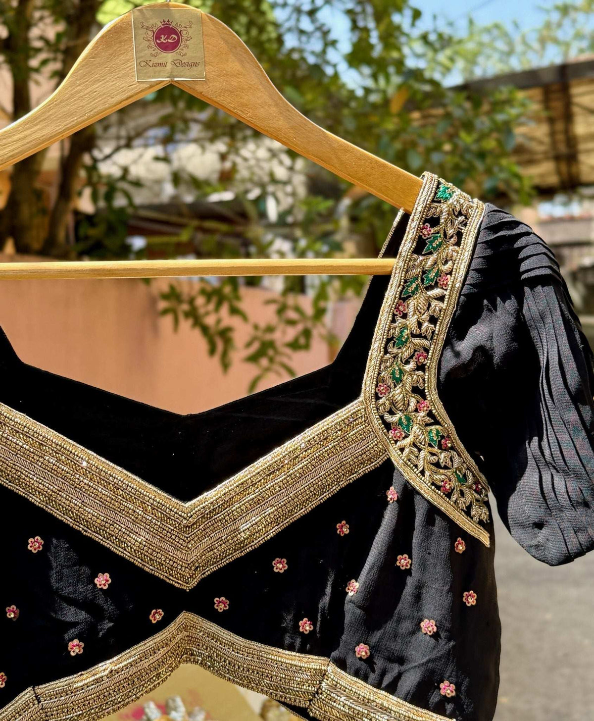 On a wooden hanger outdoors, showing the V waist border and embroidered sleeve cap